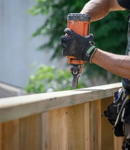 about ray and son's fence company professional fence builder using a nail gun on a wood fence